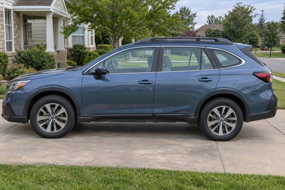 A blue grey Subaru Outback on a driveway, its windows half clear and half tinted
