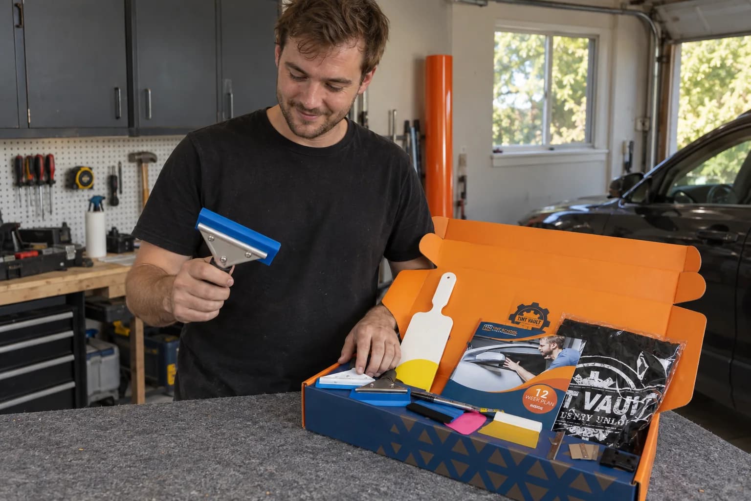 A beginner unpacking the Tint School Online tool kit in his garage