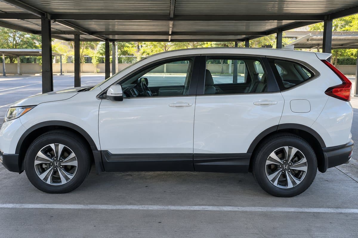 A white Honda CR-V under a covered carport, its windows half clear and half tinted