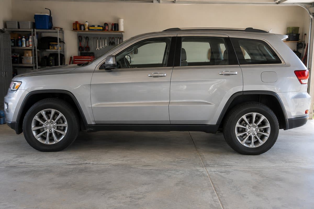 A silver Jeep Grand Cherokee in a home garage, its windows half clear and half tinted