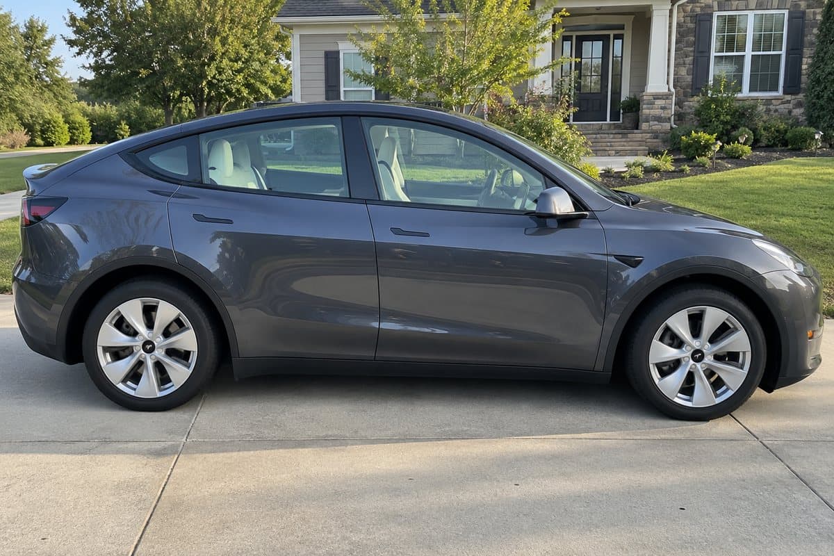 A midnight silver grey Tesla Model Y on a driveway, its windows half clear and half tinted
