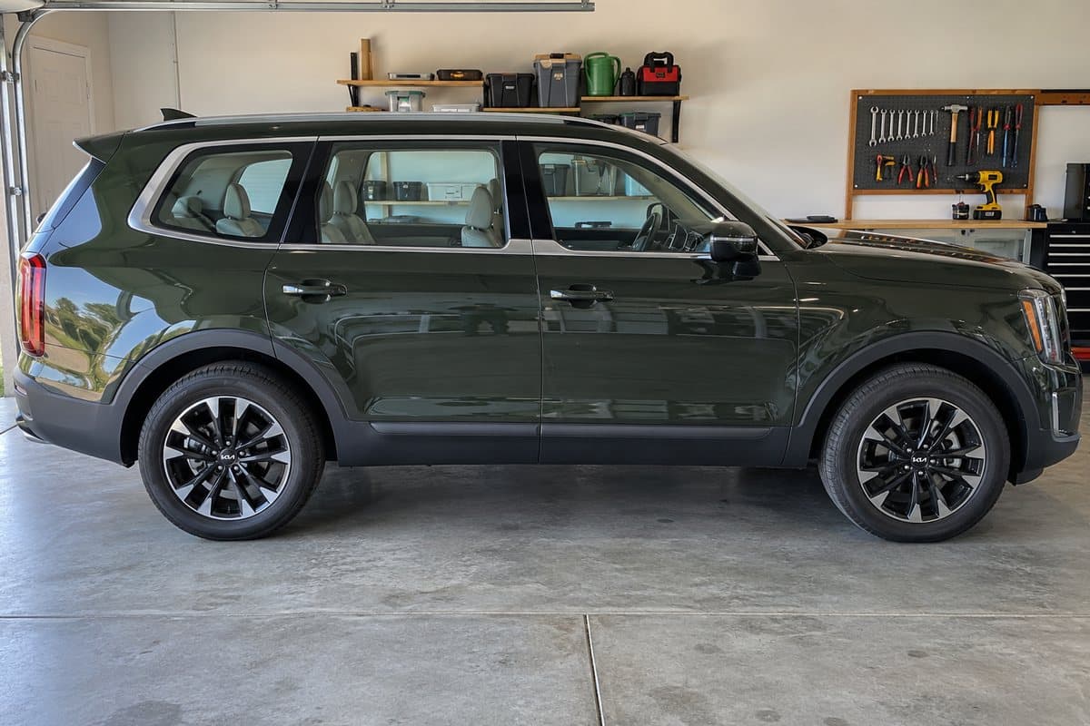 A dark green Kia Telluride in a home garage, its windows half clear and half tinted