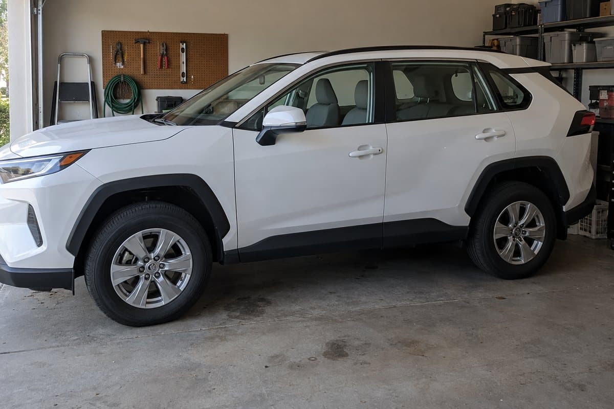 A white Toyota RAV4 in a home garage, its windows half clear and half tinted