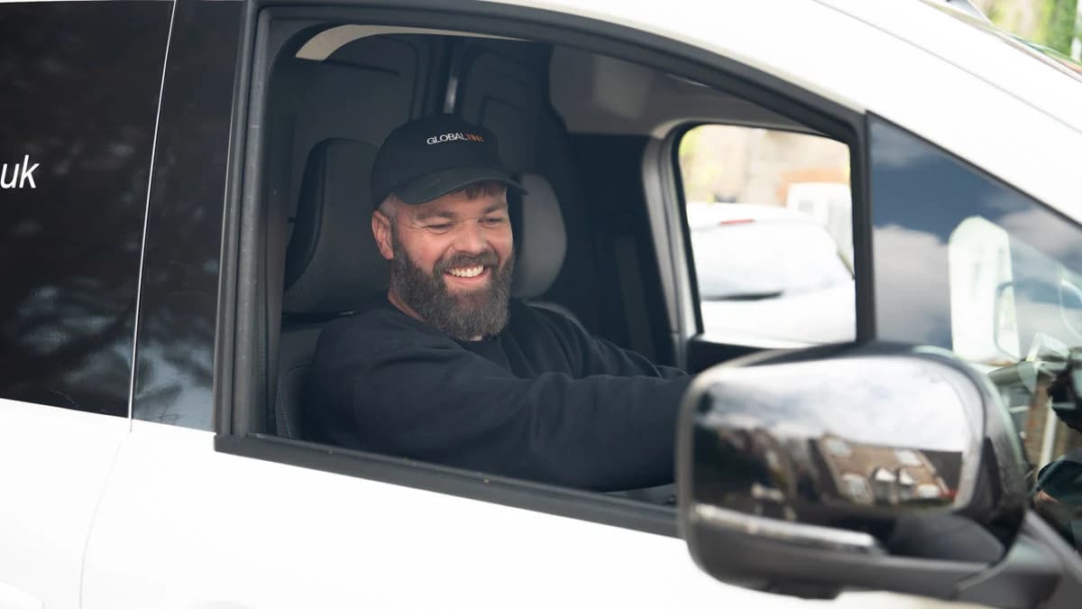Smiling Global Tint installer in a branded cap seated in a service van